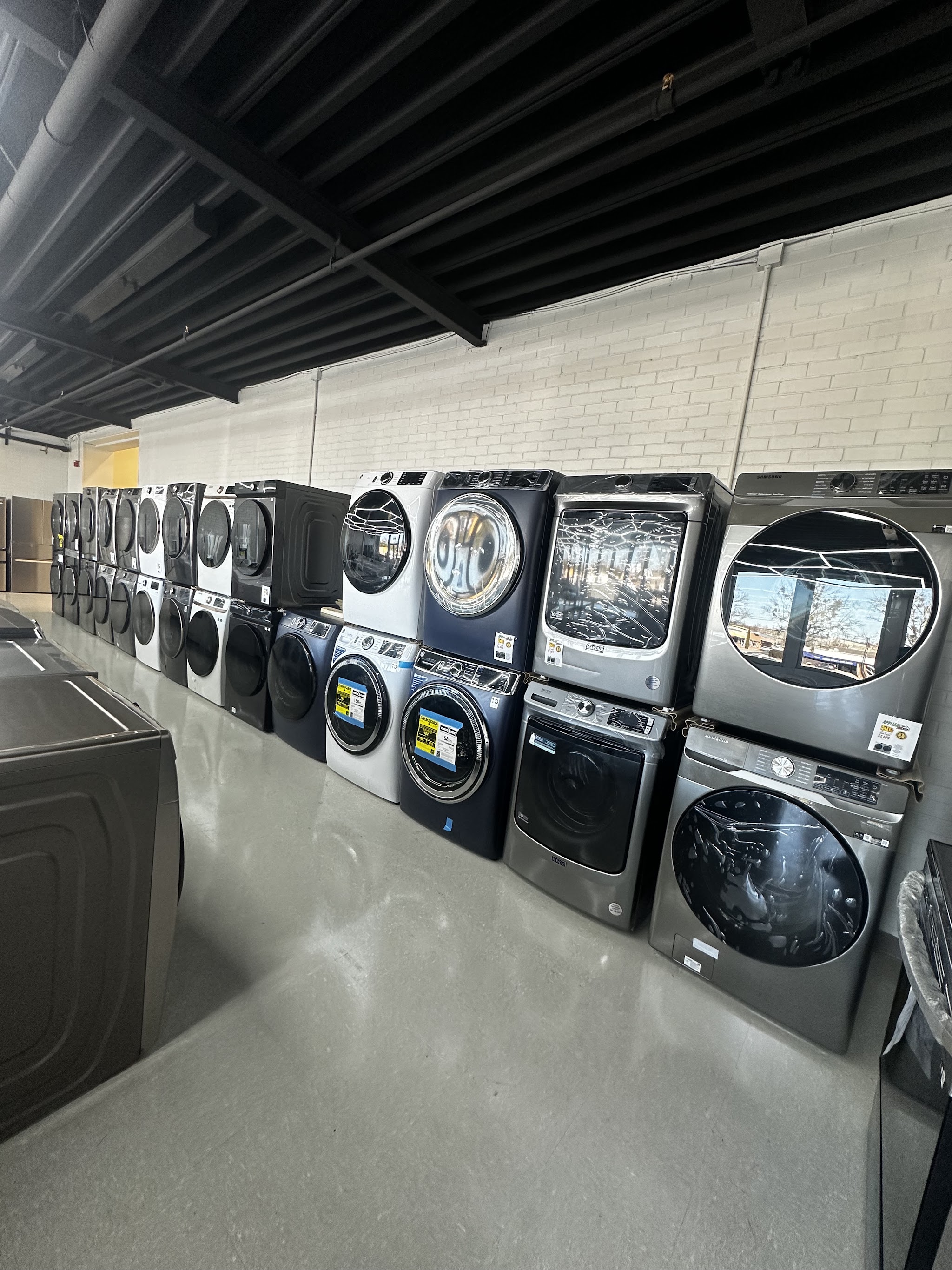Stacked washers and dryers lined up along a brick wall in our showroom
