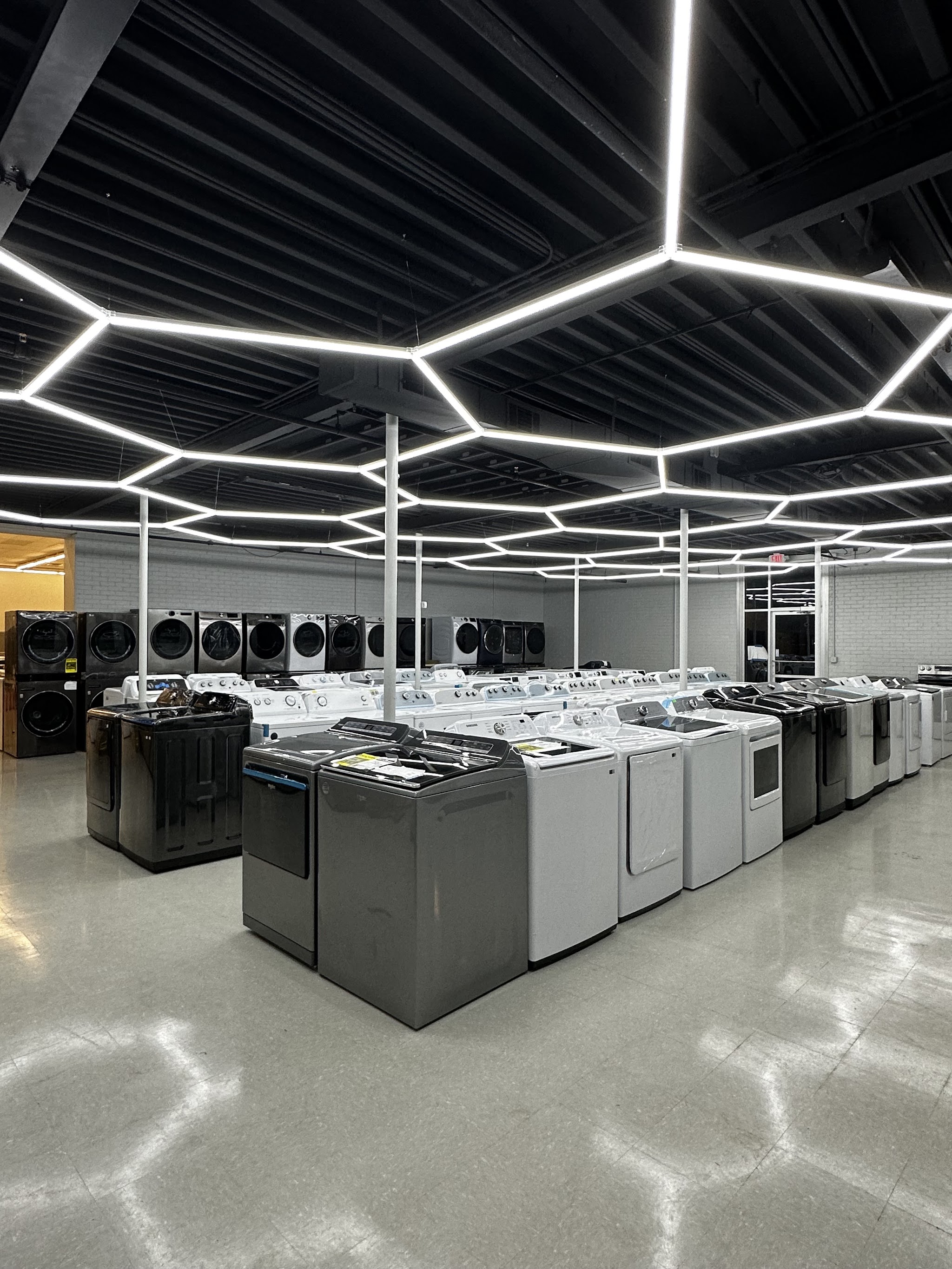 Our showroom floor with rows of washers and dryers under hexagonal ceiling lights